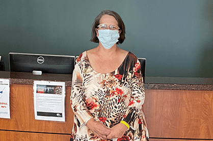 Kimberly Bush wearing a mask and standing in front of the front desk.