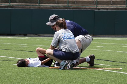 2 physical therapists assisting an athlete on the field