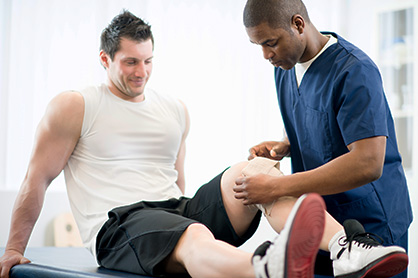 Sports physical therapy resident wrapping a patient’s knee