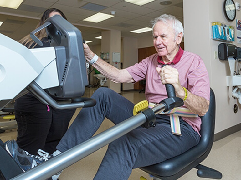 Elderly male patient using an elliptical.