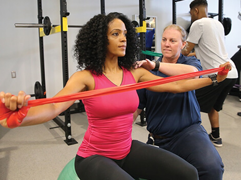 Female patient performing stretching exercises using therapy bands.